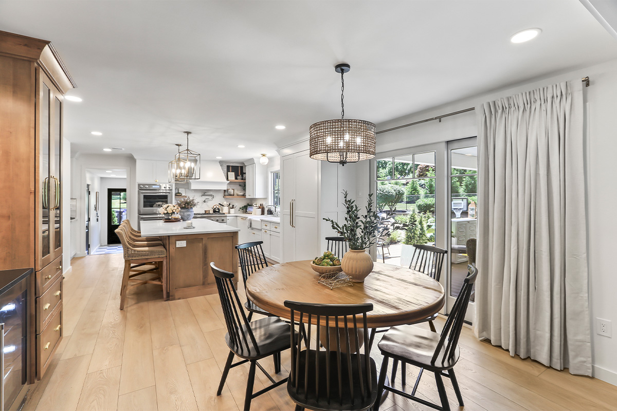 Dining room looking towards a white kitchen with light brown stained island.