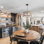Dining room with black bar cabinets with white kitchen in the background