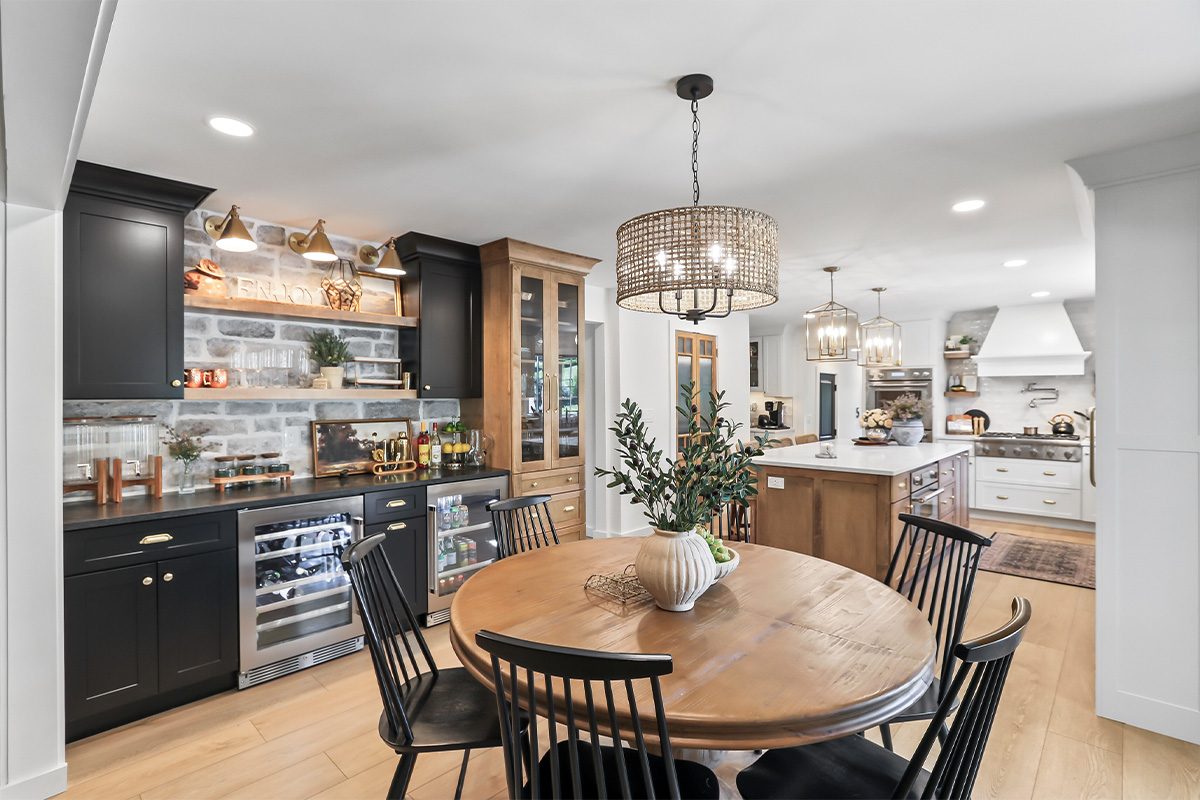 Dining room with black bar cabinets with white kitchen in the background