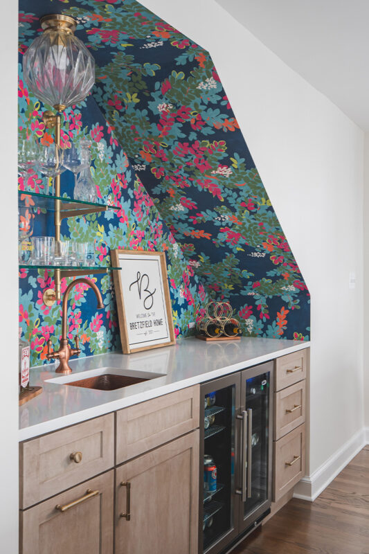 White kitchen and island with floral wallpaper in a nook