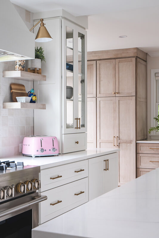 White kitchen and island with light brown stained cabinets in the distance