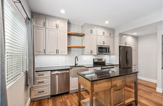 Painted Gun Smoke kitchen perimeter cabinets with a brown stained island cabinet.
