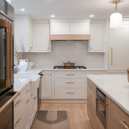 Kitchen with White perimeter cabinets and Quartersawn White Oak island cabinets stained in light brown Pampas finish.