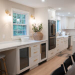 Kitchen with White perimeter cabinets and Quartersawn White Oak island cabinets stained in light brown Pampas finish.