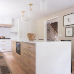 Kitchen with White perimeter cabinets and Quartersawn White Oak island cabinets stained in light brown Pampas finish.