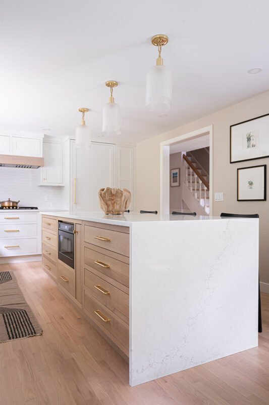 Kitchen with White perimeter cabinets and Quartersawn White Oak island cabinets stained in light brown Pampas finish.