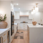 Kitchen with White perimeter cabinets and Quartersawn White Oak island cabinets stained in light brown Pampas finish.