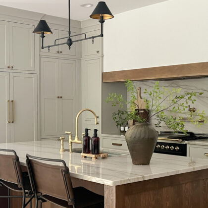 Light gray painted kitchen with white hood and stained wood island
