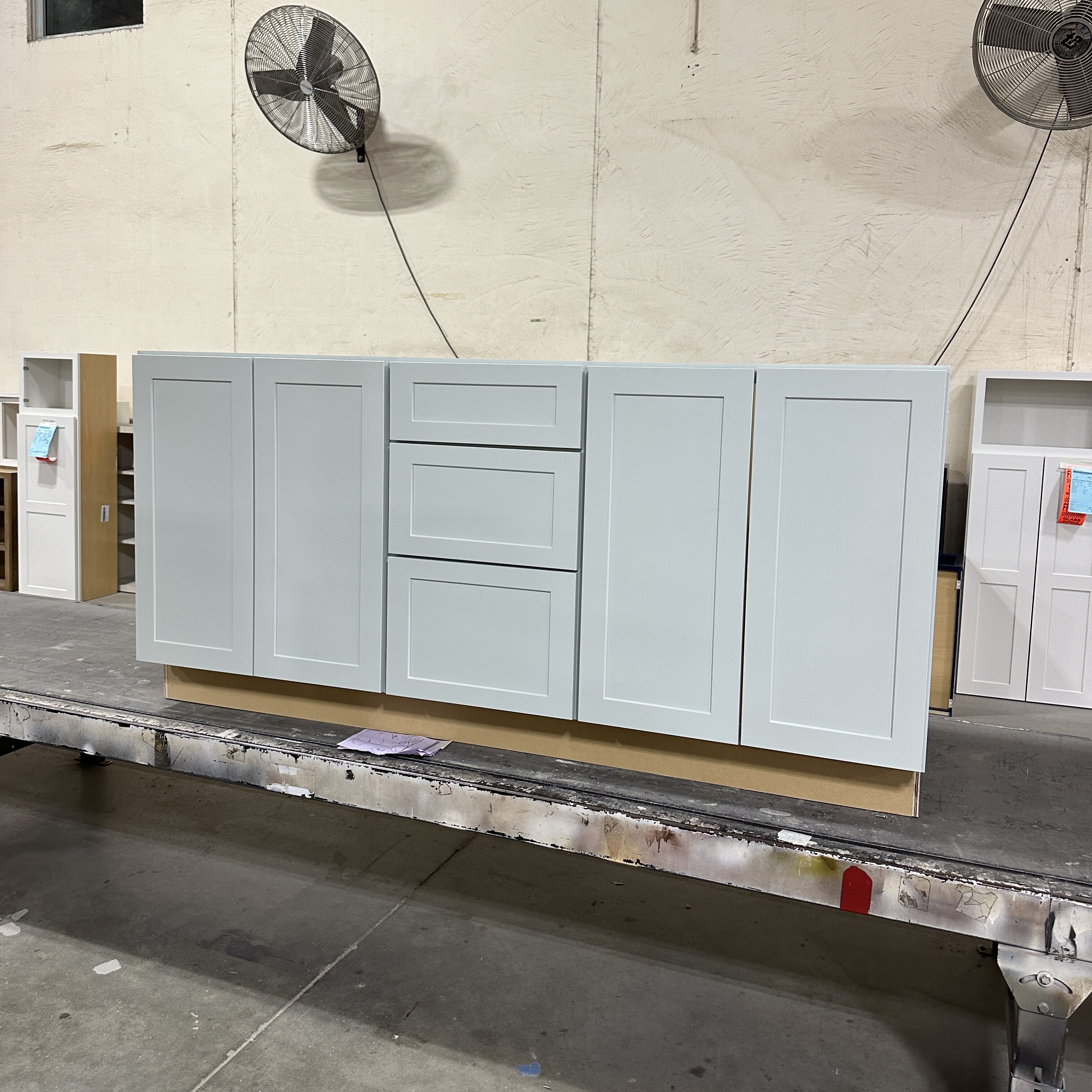Vanity cabinet with 2 sets of doors and 3 drawers in the middle painted in Sea Salt