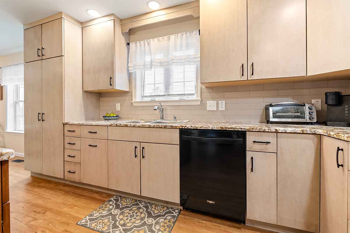 Light maple kitchen perimeter cabinets with red-stained island.