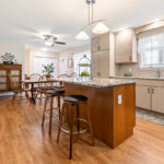 Light maple kitchen perimeter cabinets with red-stained island.
