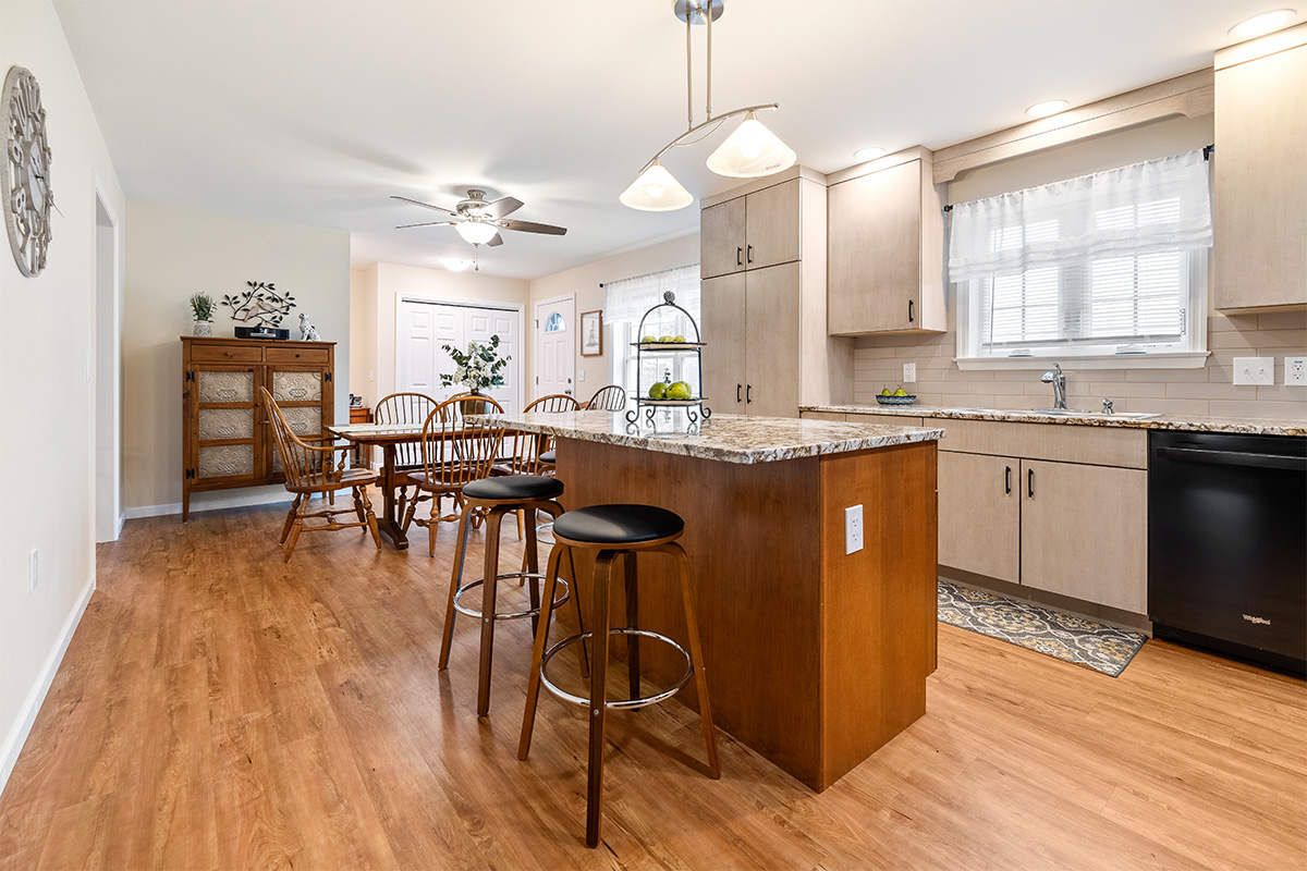 Light maple kitchen perimeter cabinets with red-stained island.