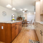 Light maple kitchen perimeter cabinets with red-stained island.