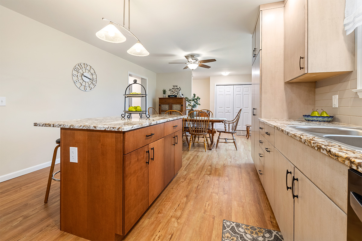 Light maple kitchen perimeter cabinets with red-stained island.