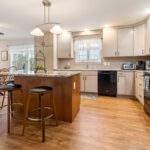 Light maple kitchen perimeter cabinets with red-stained island.