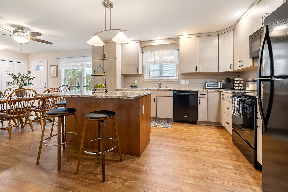 Light maple kitchen perimeter cabinets with red-stained island.