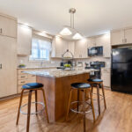 Light maple kitchen perimeter cabinets with red-stained island.