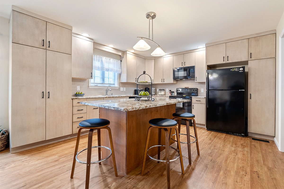 Light maple kitchen perimeter cabinets with red-stained island.