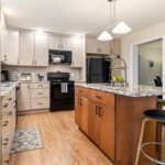 Light maple kitchen perimeter cabinets with red-stained island.