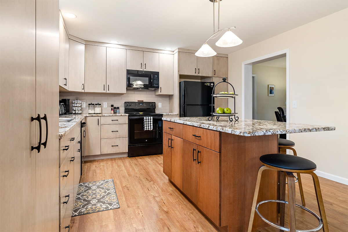 Light maple kitchen perimeter cabinets with red-stained island.