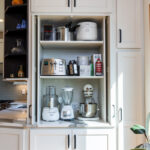 White kitchen storage cabinet that stores mixers and other appliances behind pocket doors
