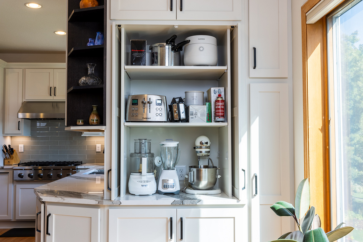 White kitchen storage cabinet that stores mixers and other appliances behind pocket doors