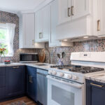 White and blue kitchen cabinets. View of the stove and wood hood.