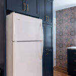 Blue kitchen cabinets surrounding a white fridge.