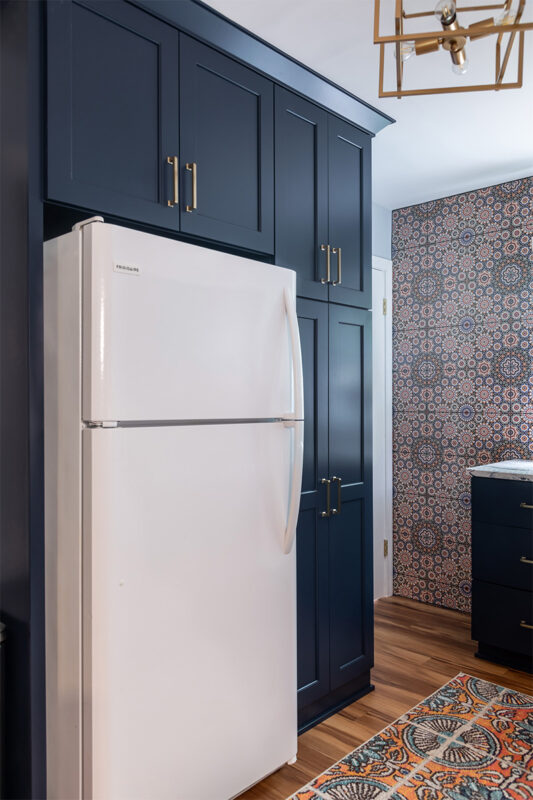Blue kitchen cabinets surrounding a white fridge.