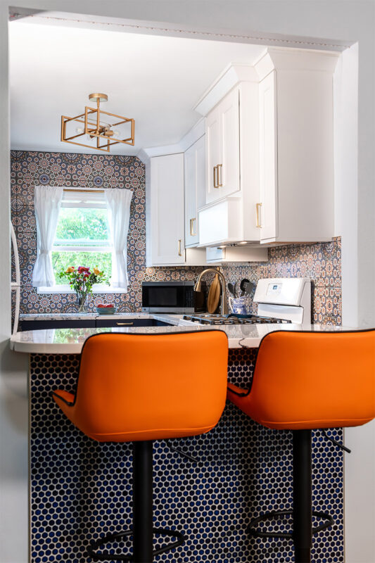 White and blue kitchen cabinets. Orange peninsula seats.