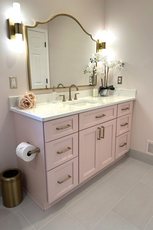Pink bathroom with pink tile and single-sink vanity and gold rimmed mirror
