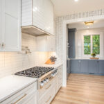 White kitchen cabinets with a view towards a blue painted pantry