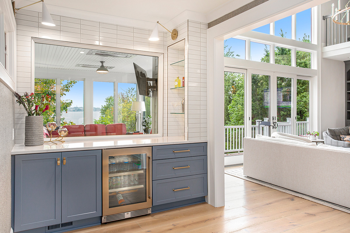 Blue painted bar cabinets with large living room with full height windows.