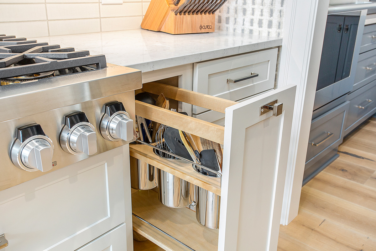White kitchen cabinet with pull-out utensil storage beside the cook top range