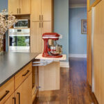 Light brown stained kitchen with pop-up stand mixer storage.