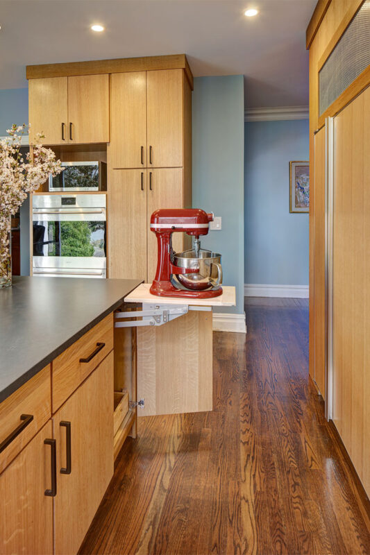 Light brown stained kitchen with pop-up stand mixer storage.