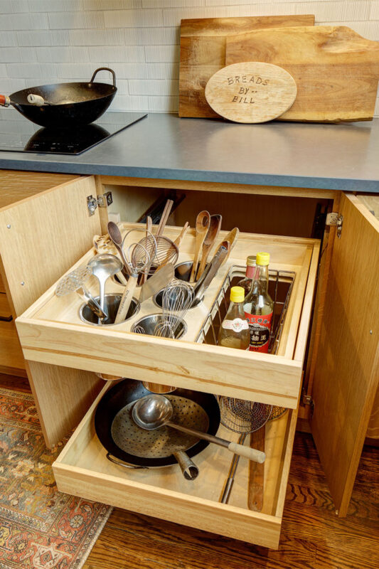 Base cabinet with roll trays pulled out showing utensils, etc.