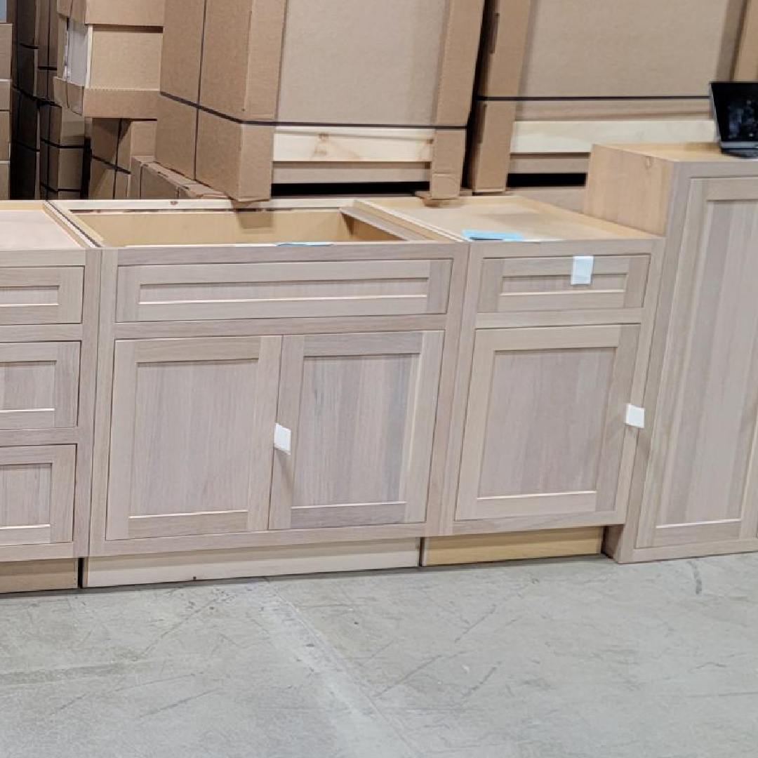 Standard base cabinets in a light finish in a warehouse setting.