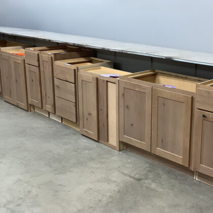Several cabinets in the light brown Sparrow finish placed on a warehouse floor.