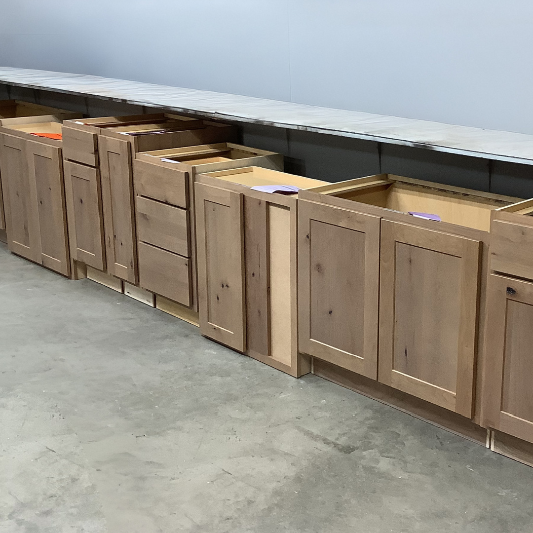 Several cabinets in the light brown Sparrow finish placed on a warehouse floor.