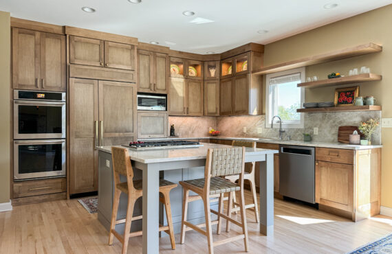 Cashew-stained kitchen perimeter cabinets and gray-painted island with legs and stools.