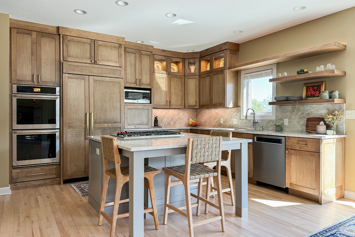 Cashew-stained kitchen perimeter cabinets and gray-painted island with legs and stools.