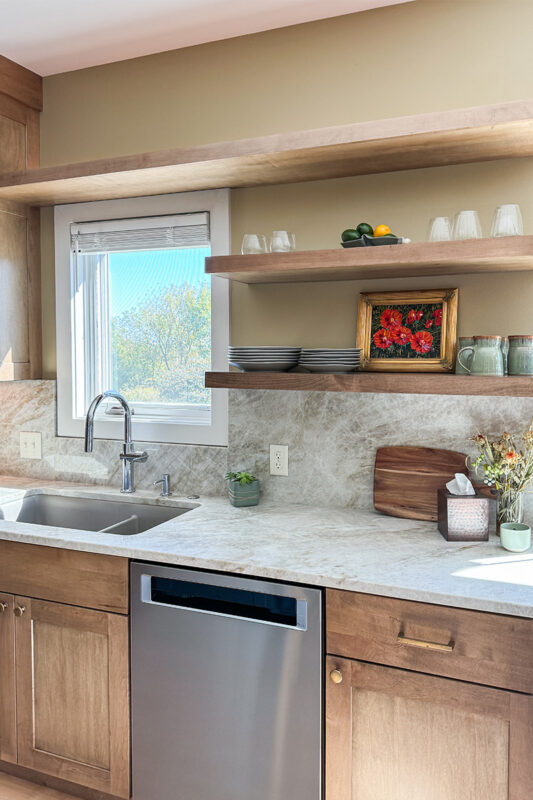 Cashew-stained floating shelves above cabinets, dishwasher and sink
