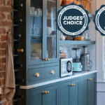 Purple painted bar cabinets with wine bottles and open shelves. Includes badge notifying that this project is a design contest winner.