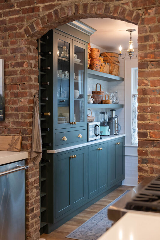 Purple painted bar cabinets with wine bottles and open shelves.