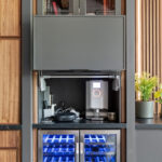 Contemporary entertainment center with gray painted cabinets and stained slatted back wall behind a large mounted tv.