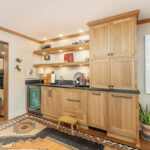 Bar with light brown stained cabinets and floating shelves.