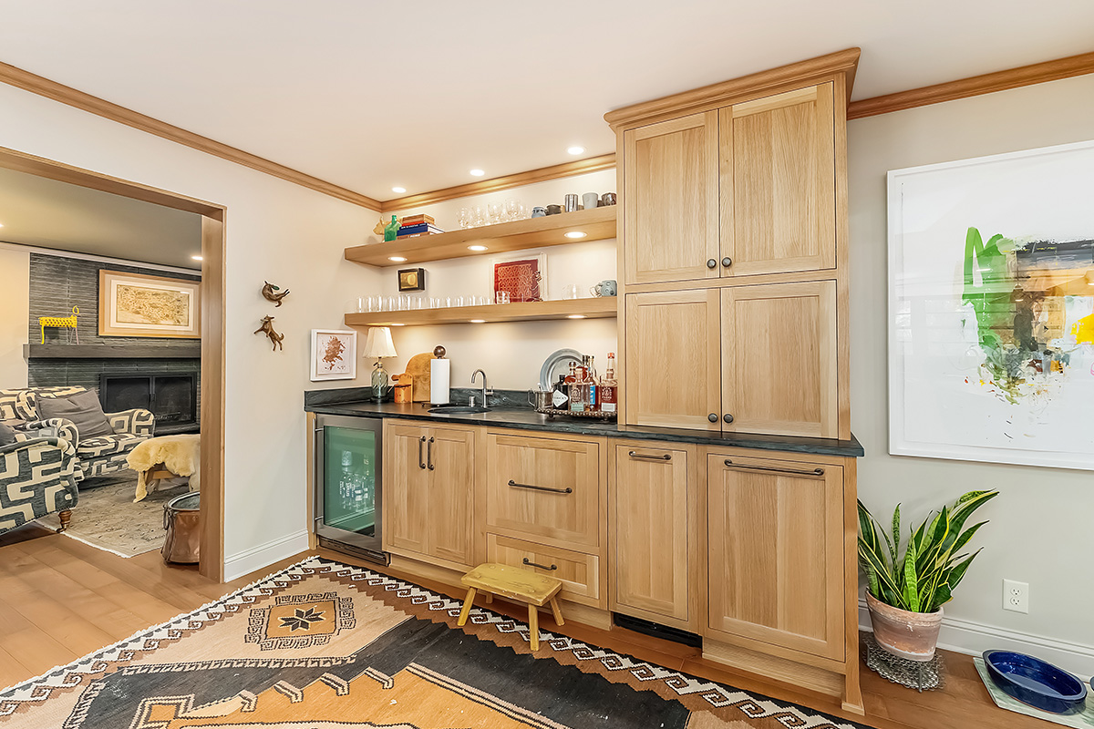 Bar with light brown stained cabinets and floating shelves.