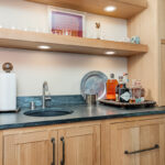 Bar with light brown stained cabinets and floating shelves.