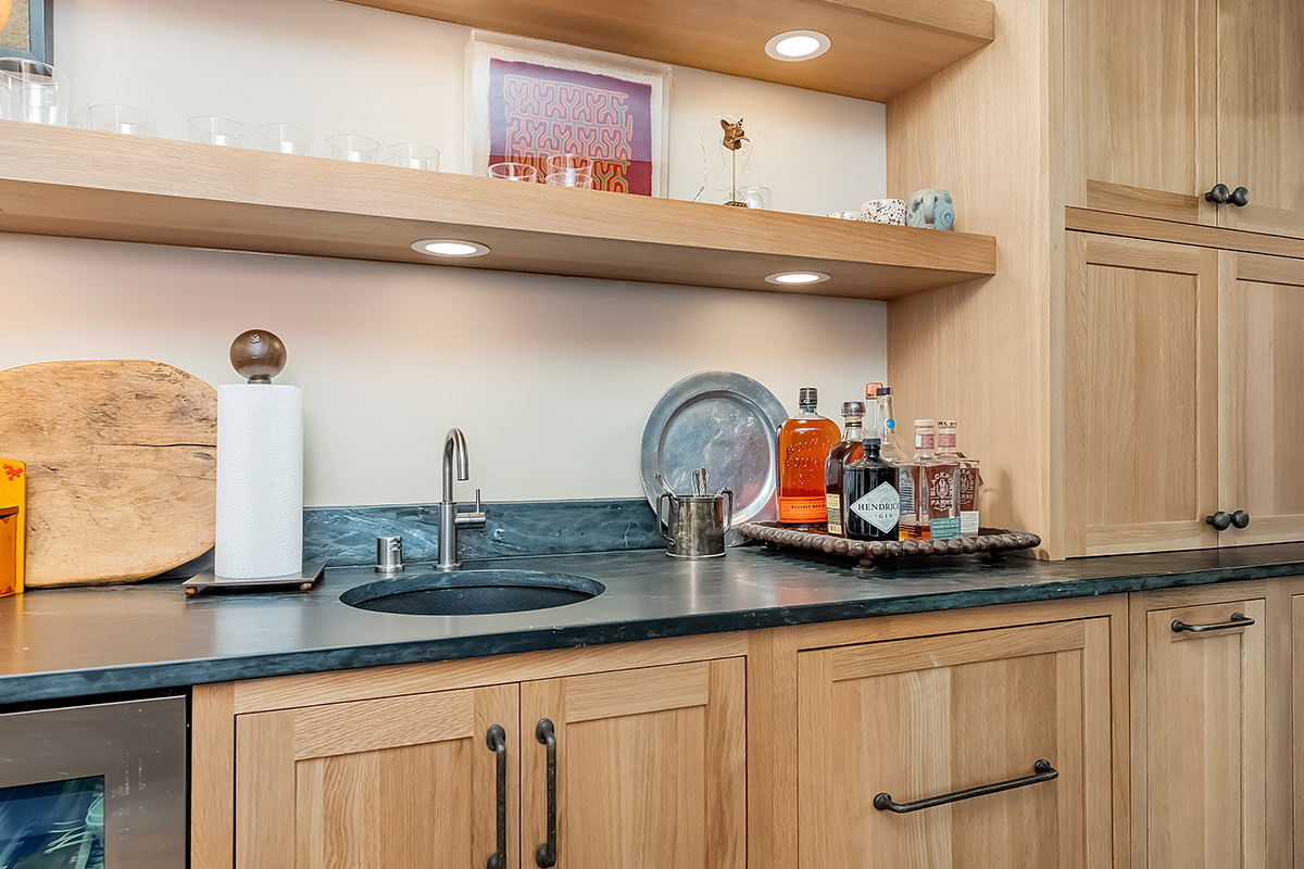 Bar with light brown stained cabinets and floating shelves.